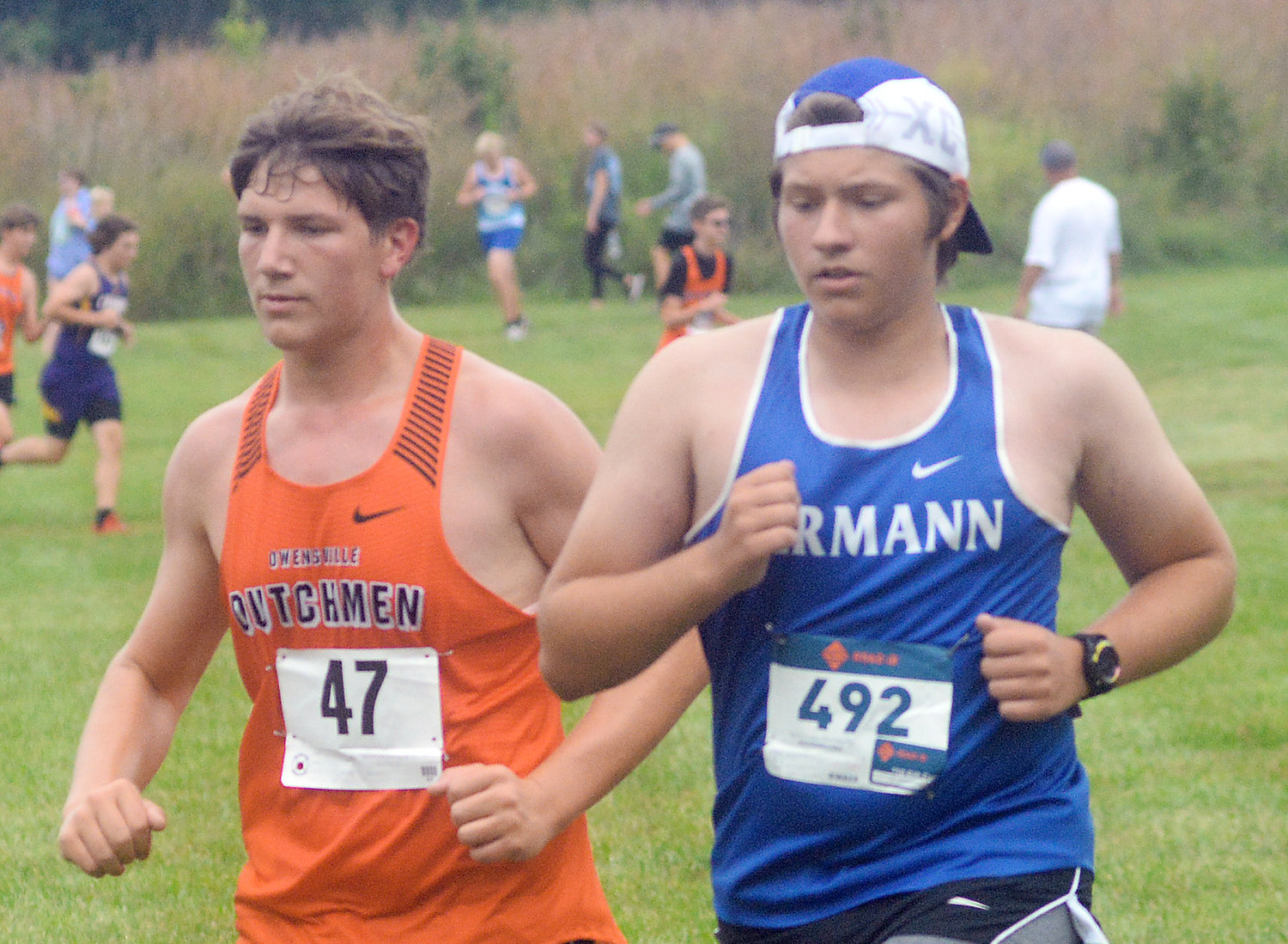Eli Graham (left) runs right next to Hermann’s Isaiah Brown during the junior varsity boys race at the New Haven Cross Country Invitational Saturday morning at New Haven City Park.